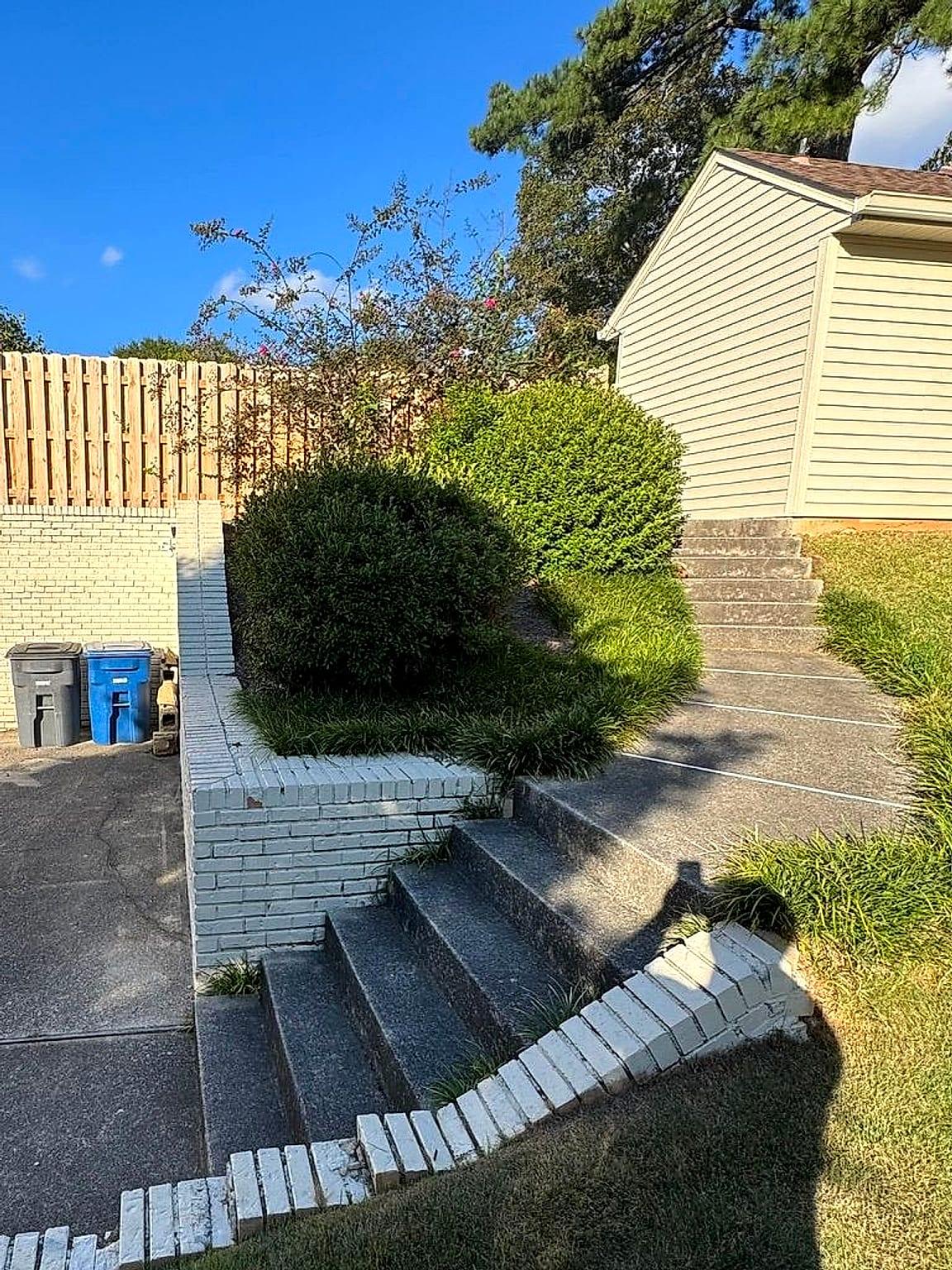 Dark, dirty concrete steps and walkway beside a white brick planter