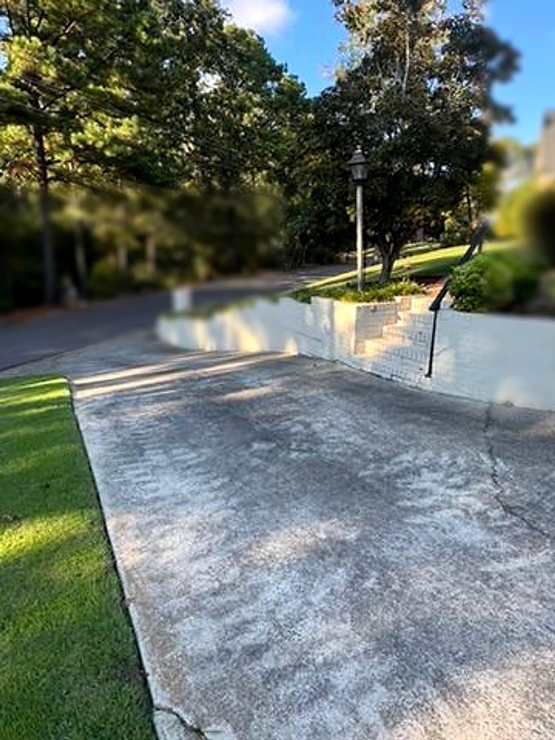 Stained driveway beside a white brick retaining wall and steps