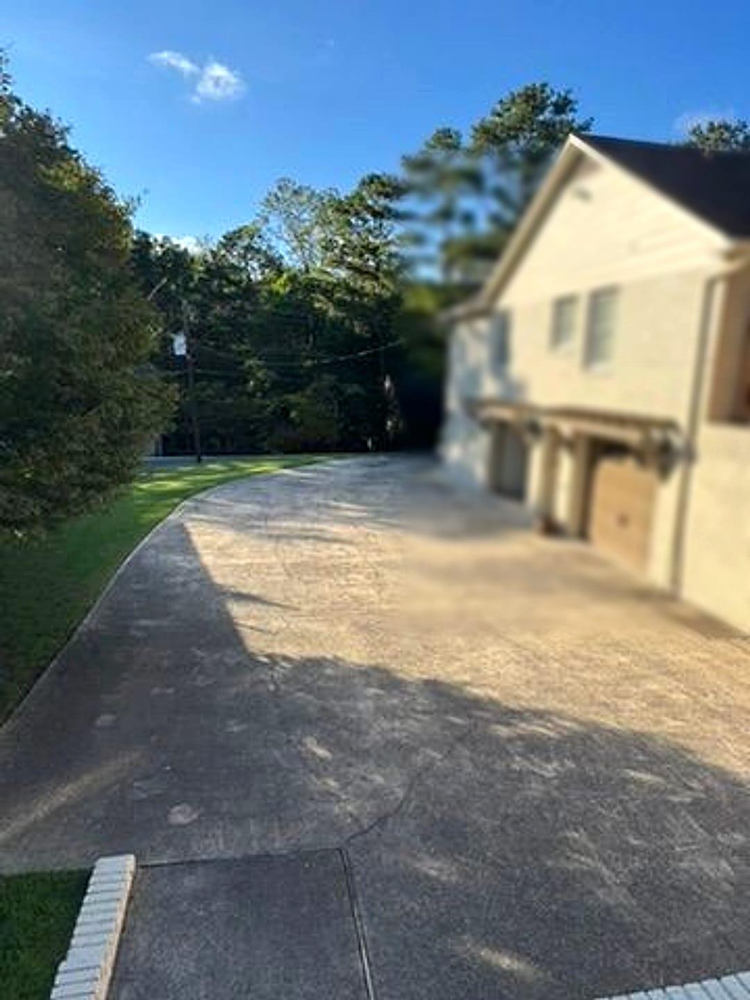 Long concrete driveway darkened with grime leading to a two-car garage
